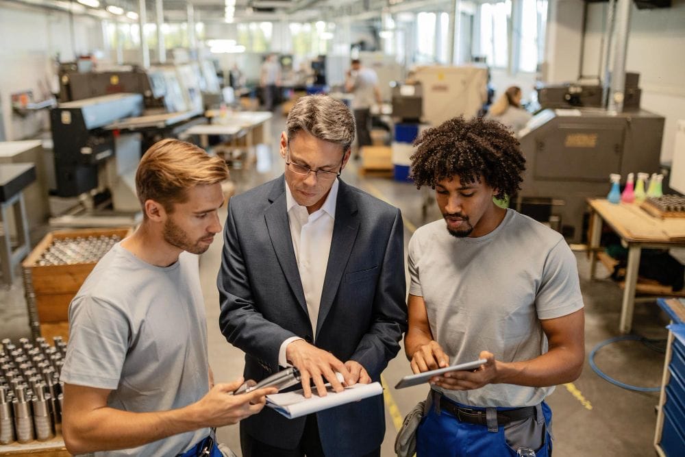 Engineer and industrial workers reviewing quality reports together