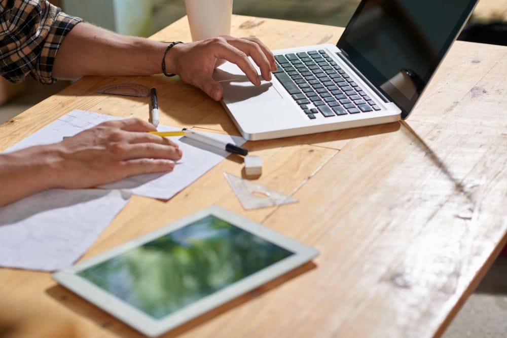 Contractor using a laptop while reviewing project paperwork