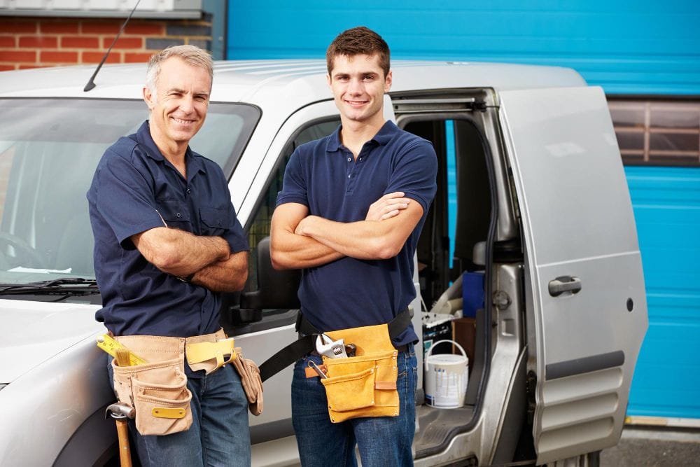 Service contractors standing together beside their work van