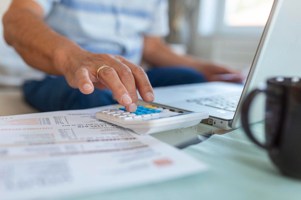 person calculating expenses beside laptop