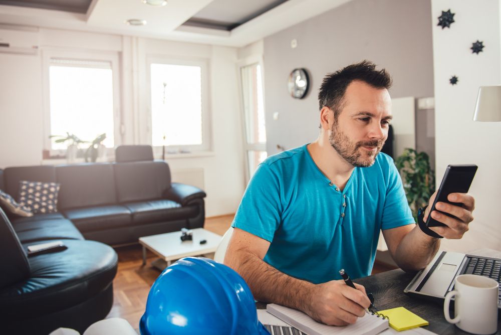 Tradesperson using a smartphone while taking work notes