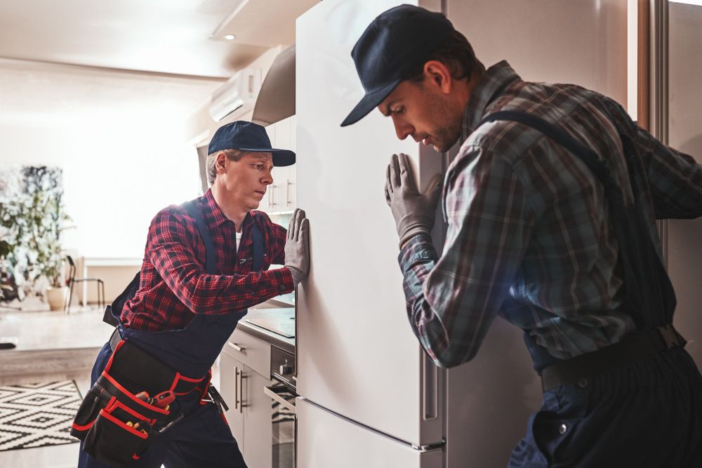 Home repair technicians inspecting a refrigerator