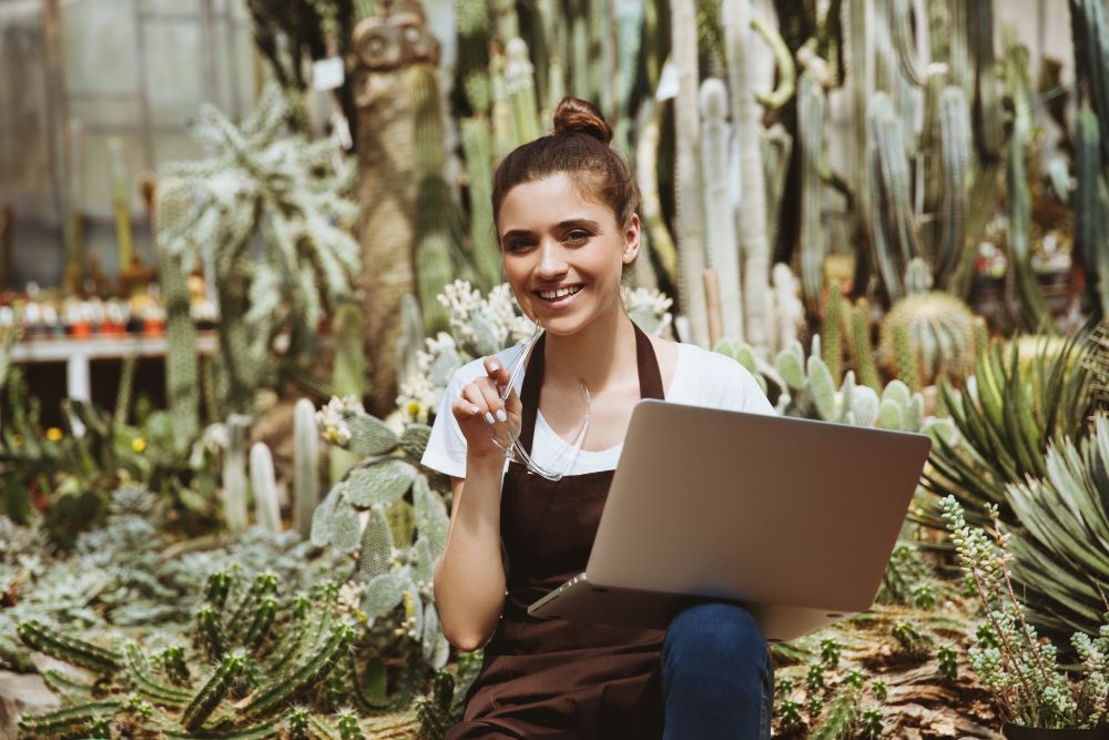 Landscaping professional using a laptop in a greenhouse