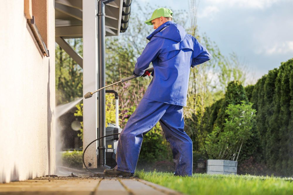 Pressure washing technician cleaning a residential house exterior