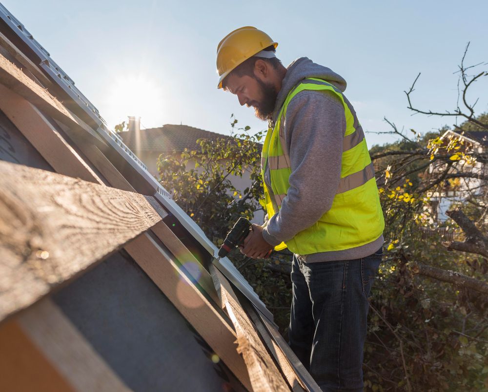 Roofer using a drill while working on a residential roof