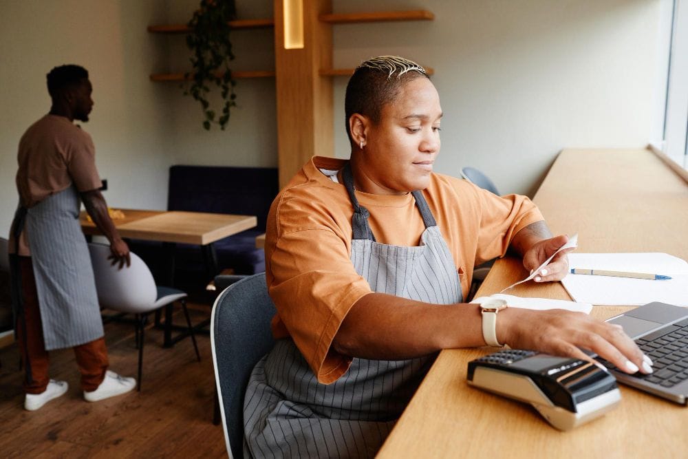 Small business owner managing financial records while working in a cafe