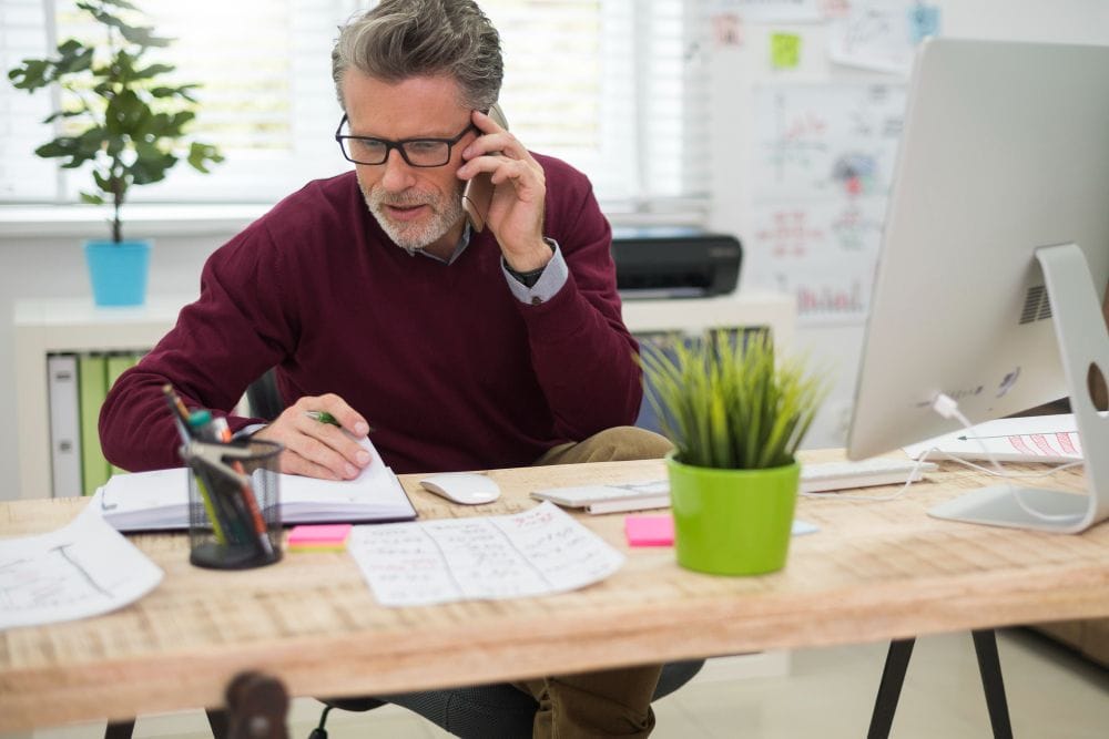 Self-employed professional reviewing paperwork while using quicken vs quickbooks and speaking with a client