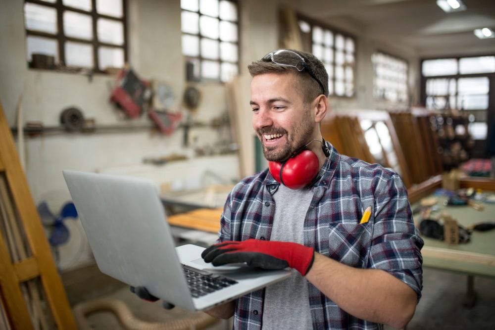 Carpenter using a laptop while working in a workshop