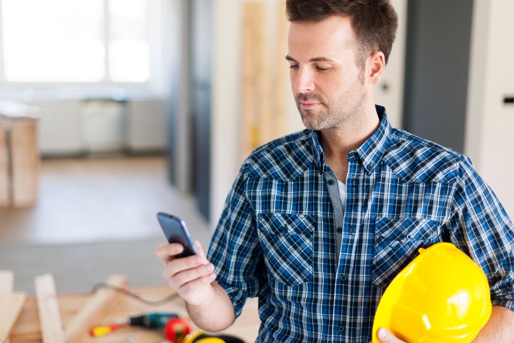 Service technician using a smartphone while working outdoors