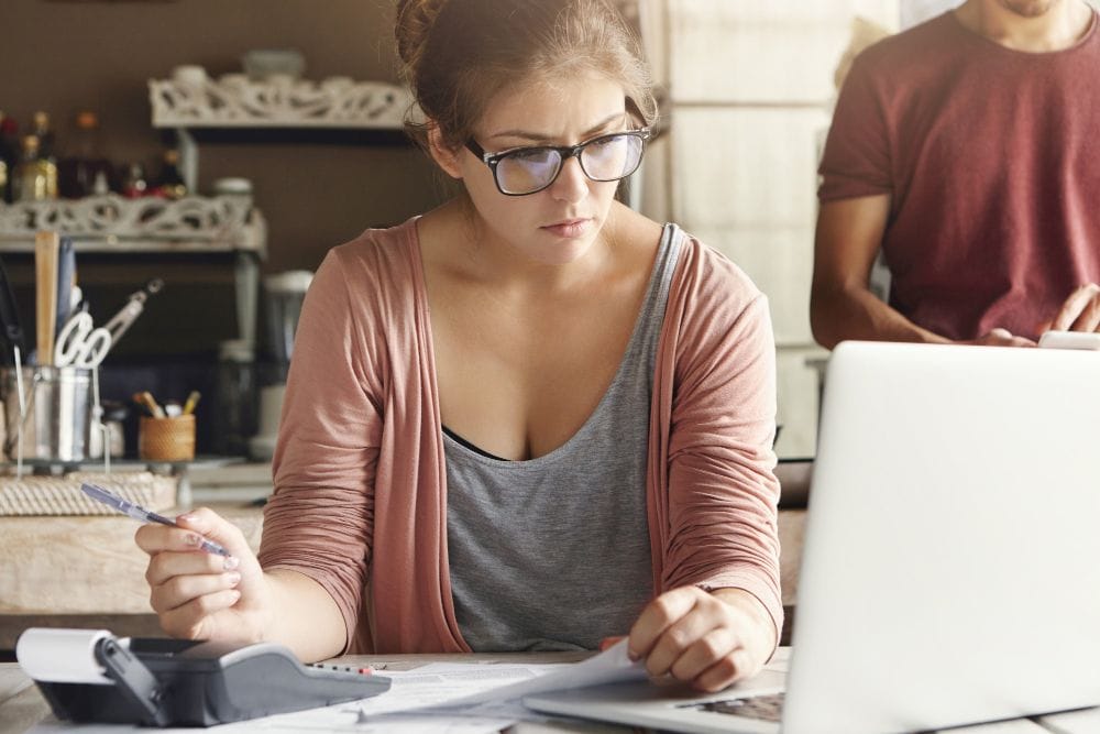 Business owner reviewing bills and financial records on a laptop