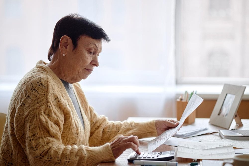 Business owner reviewing invoices and calculating expenses at a desk