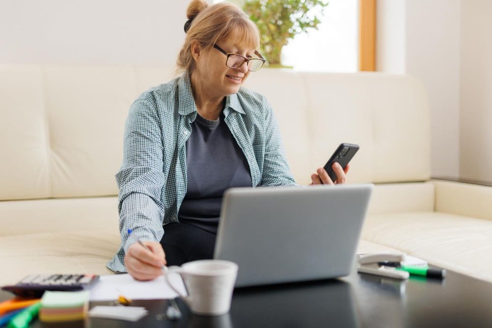Business owner using a laptop with invoice fly vs invoice2go while speaking with a client by phone