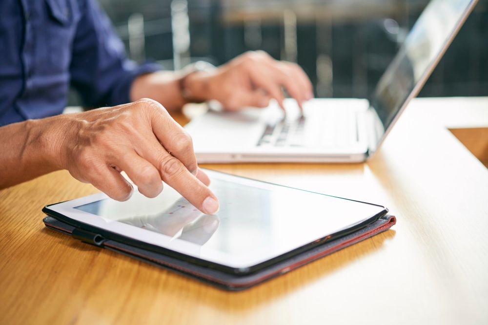 professional using a tablet beside laptop