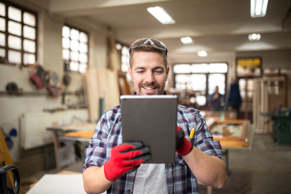 Tradesperson using a tablet while planning work in a workshop